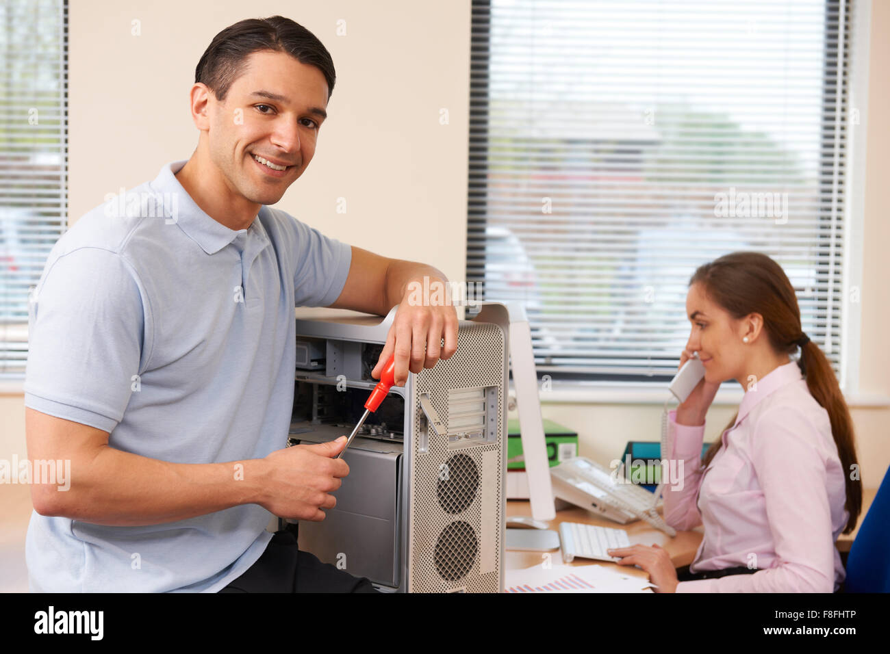 Computer IT Support Worker Fixing Machine In Office Stock Photo