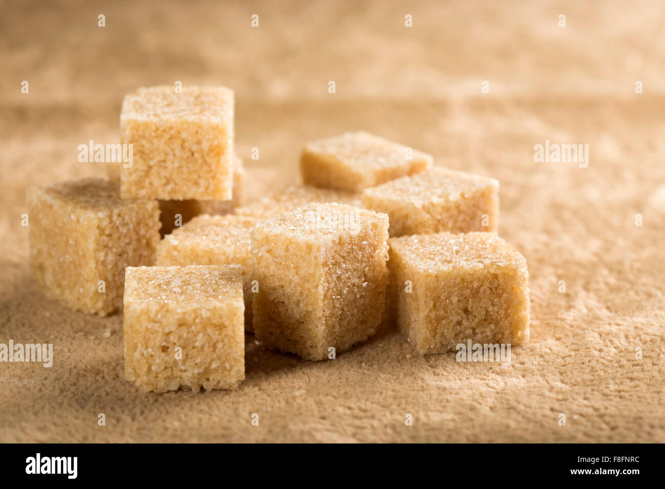 Brown cane sugar cubes on a brown background Stock Photo