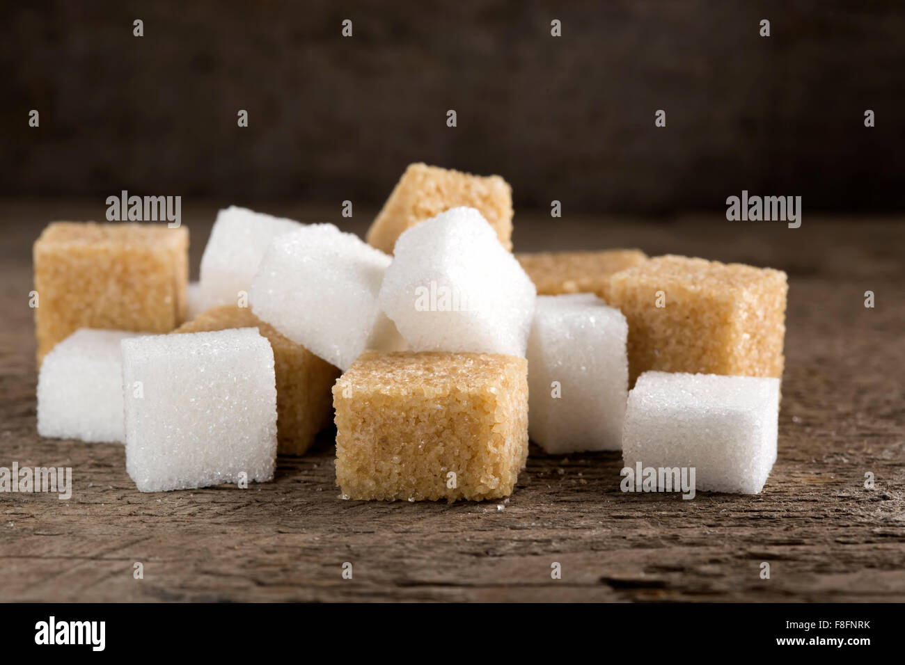 Cubes of sugar cane brown and white refined over rustic wooden background Stock Photo