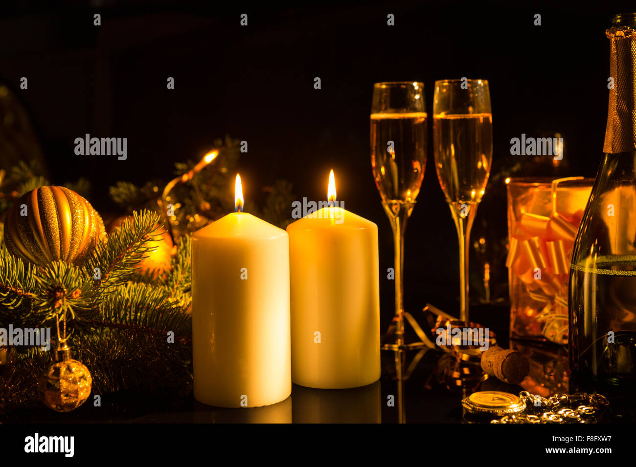 Romantic Still Life of Lit Candles Illuminating Glasses of Champagne on Dark Background with Christmas Decorations and Gifts - Sentimental Image of Festive Burning Candles in Warm Light. Stock Photo