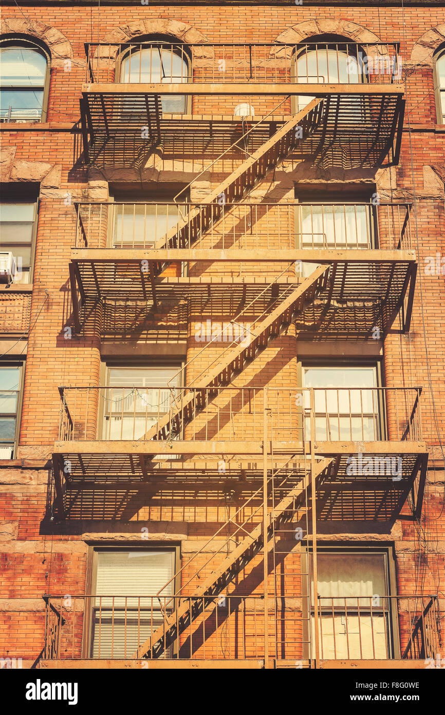 Retro style photo of New York building with fire escape ladders, USA. Stock Photo