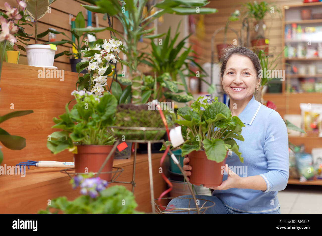 Happy mature woman chooses primula  in flower store Stock Photo