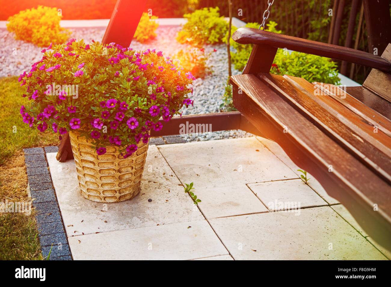 Flowers Garden Decoration. Decorative Flower Pot and Wooden Swing Closeup. Stock Photo