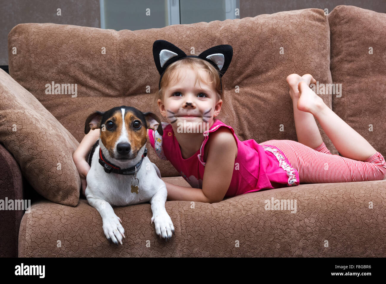 Little Girl With Cat Face Painting Embrace Her Dog Stock Photo