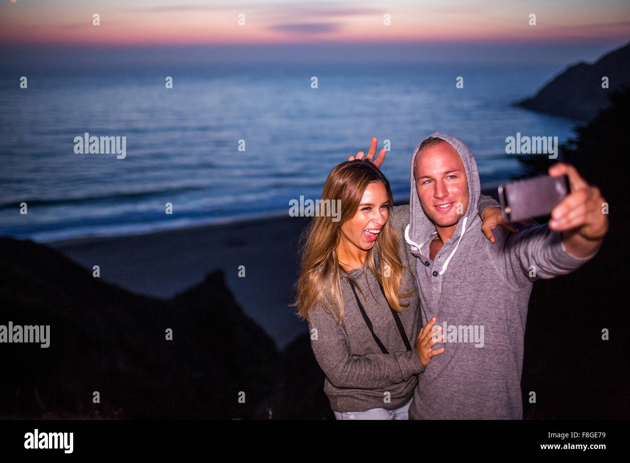 Caucasian couple taking selfie at beach Stock Photo