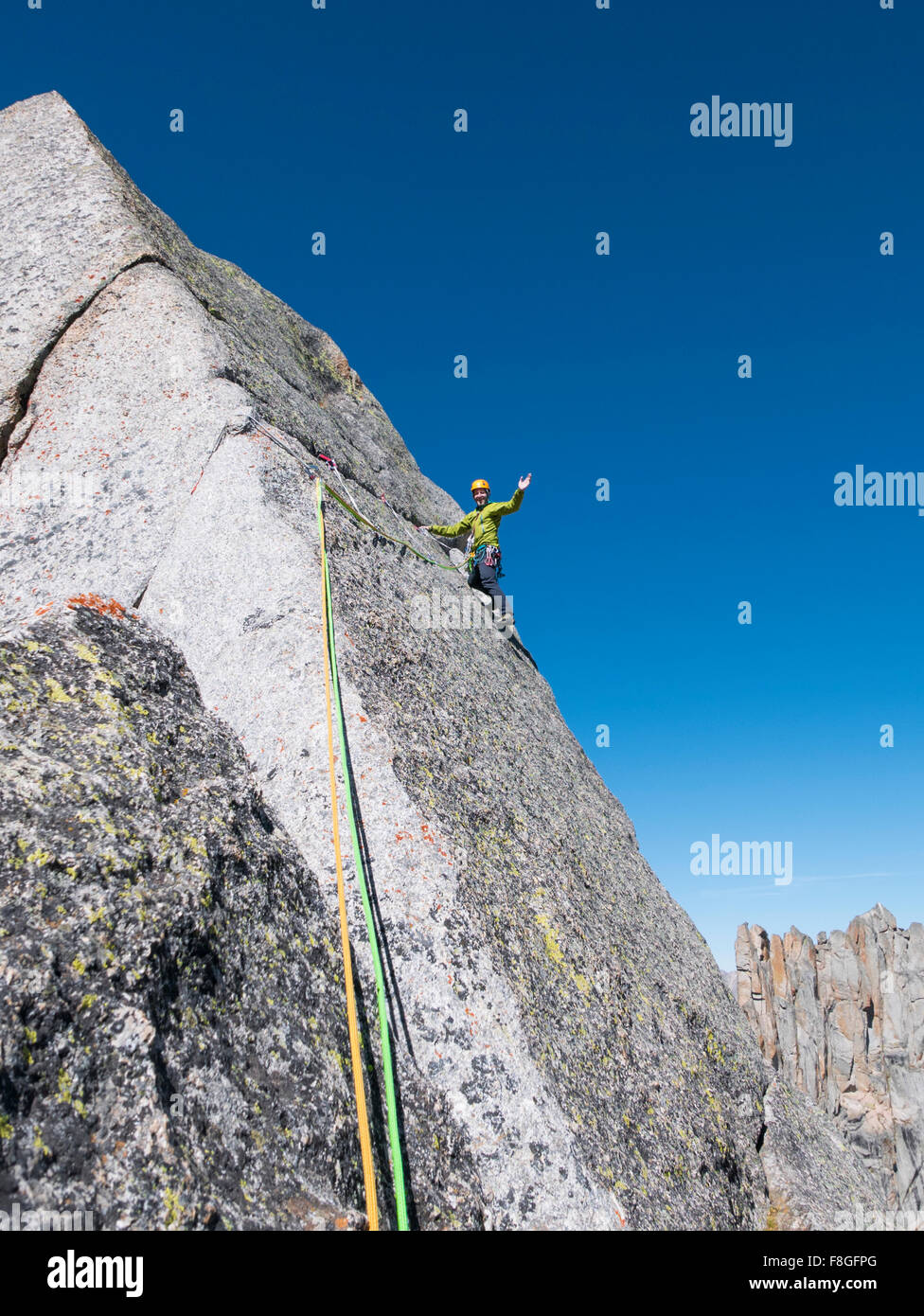 Caucasian climber waving on mountainside Stock Photo