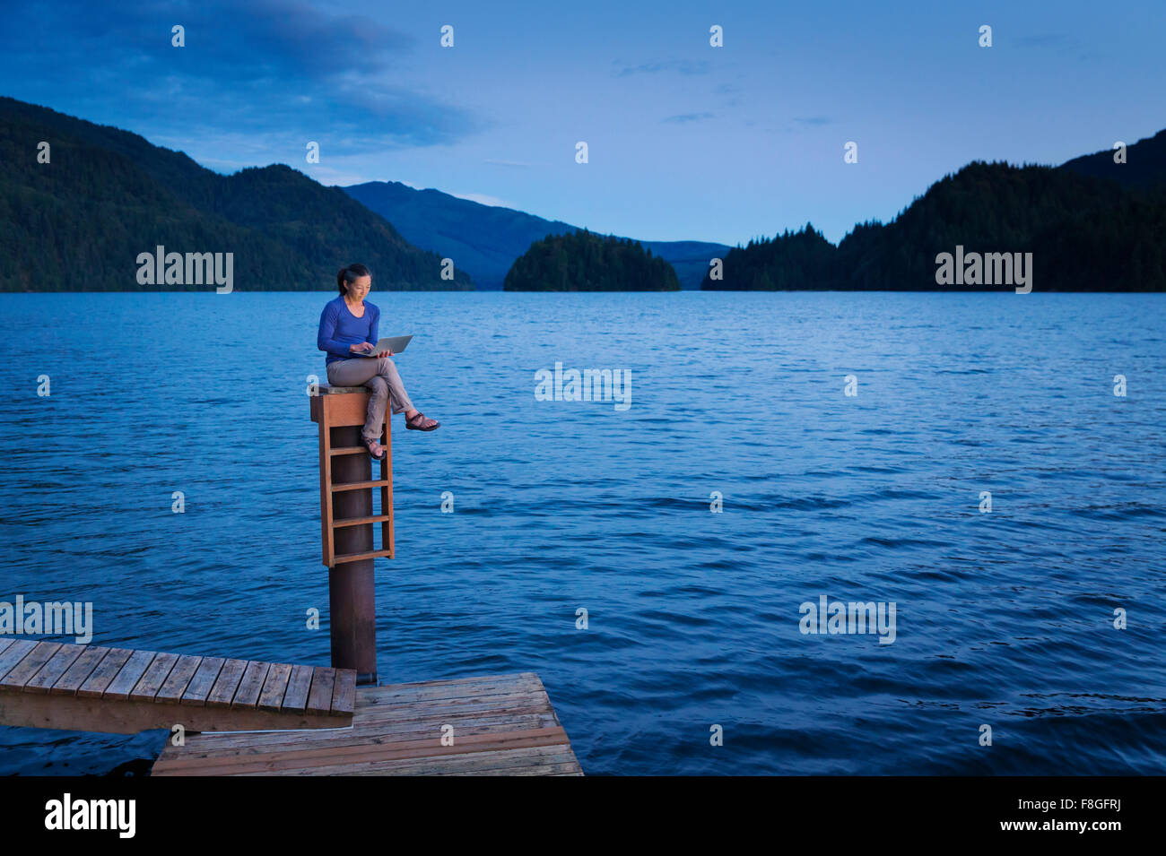 Japanese woman sitting on wooden dock at lake Stock Photo