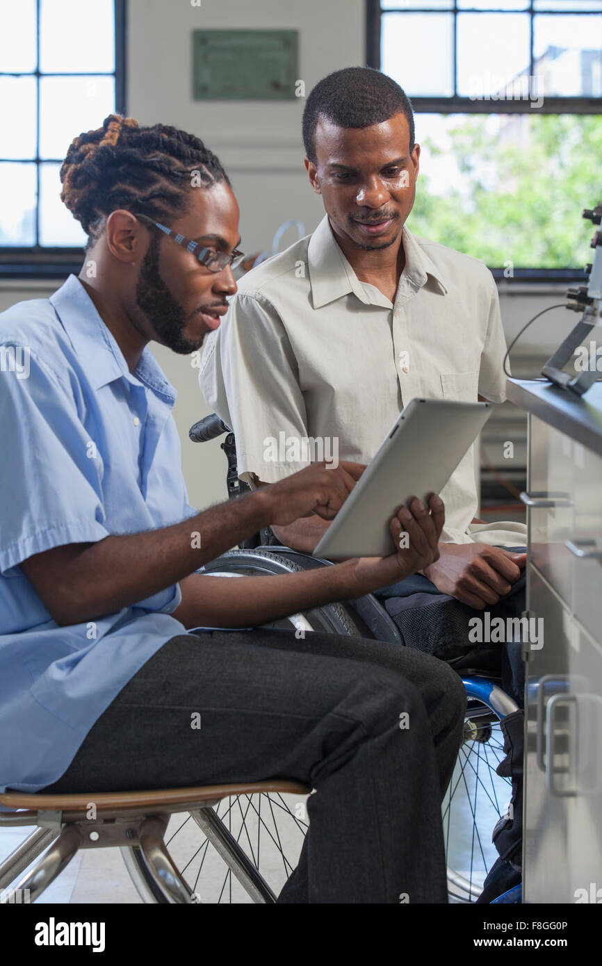 Paraplegic student and classmate using digital tablet Stock Photo