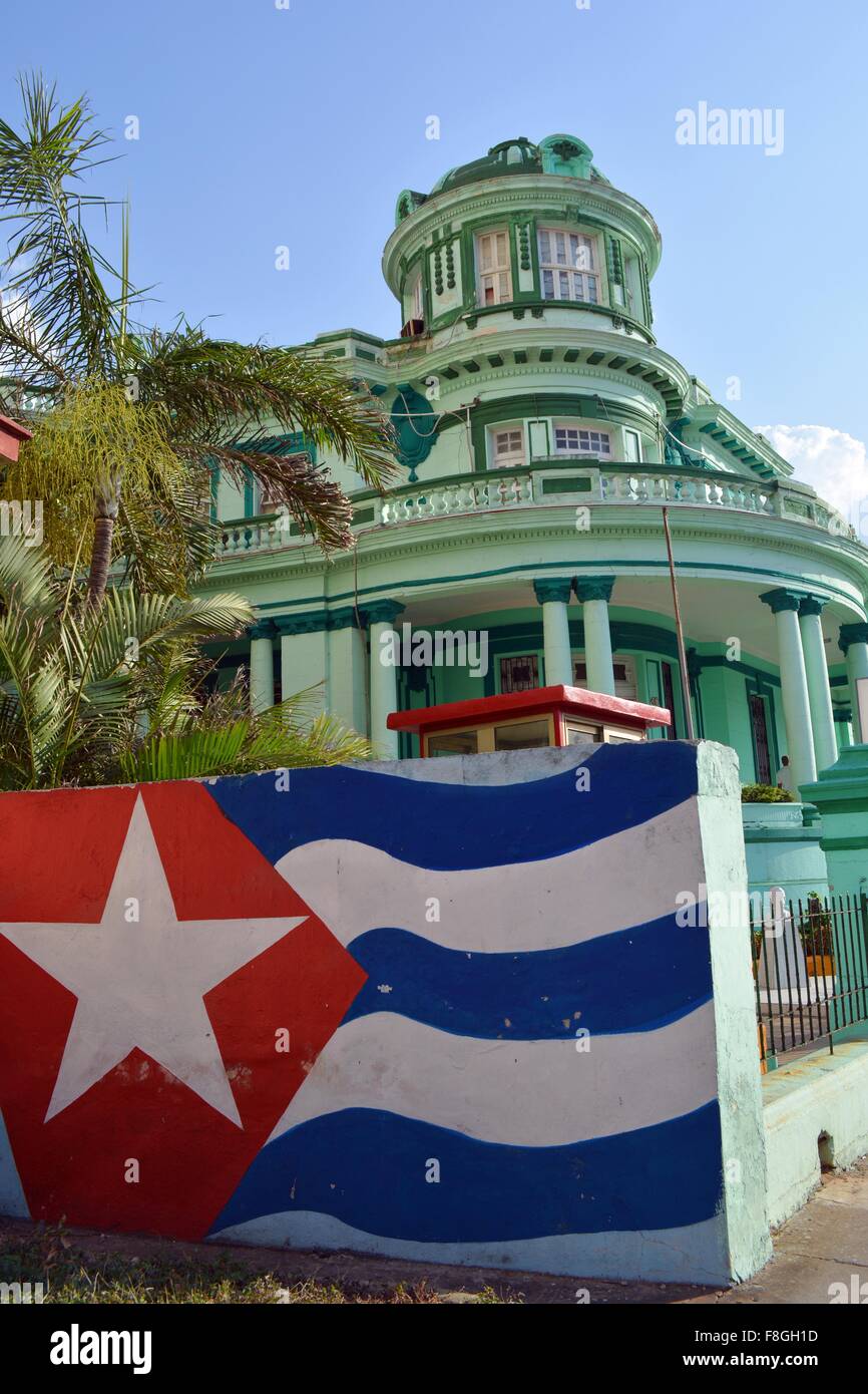 colorful colonial municipal building in Havana with a Cuban flag mural and palm trees in the sun Stock Photo