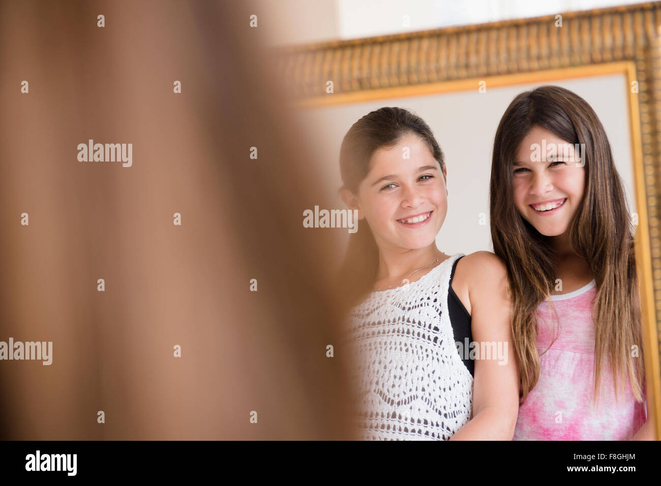 Caucasian twin sisters admiring themselves in mirror Stock Photo