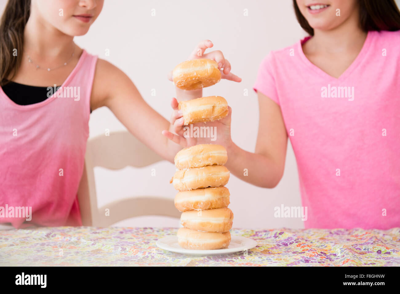 Caucasian twin sisters eating donuts Stock Photo