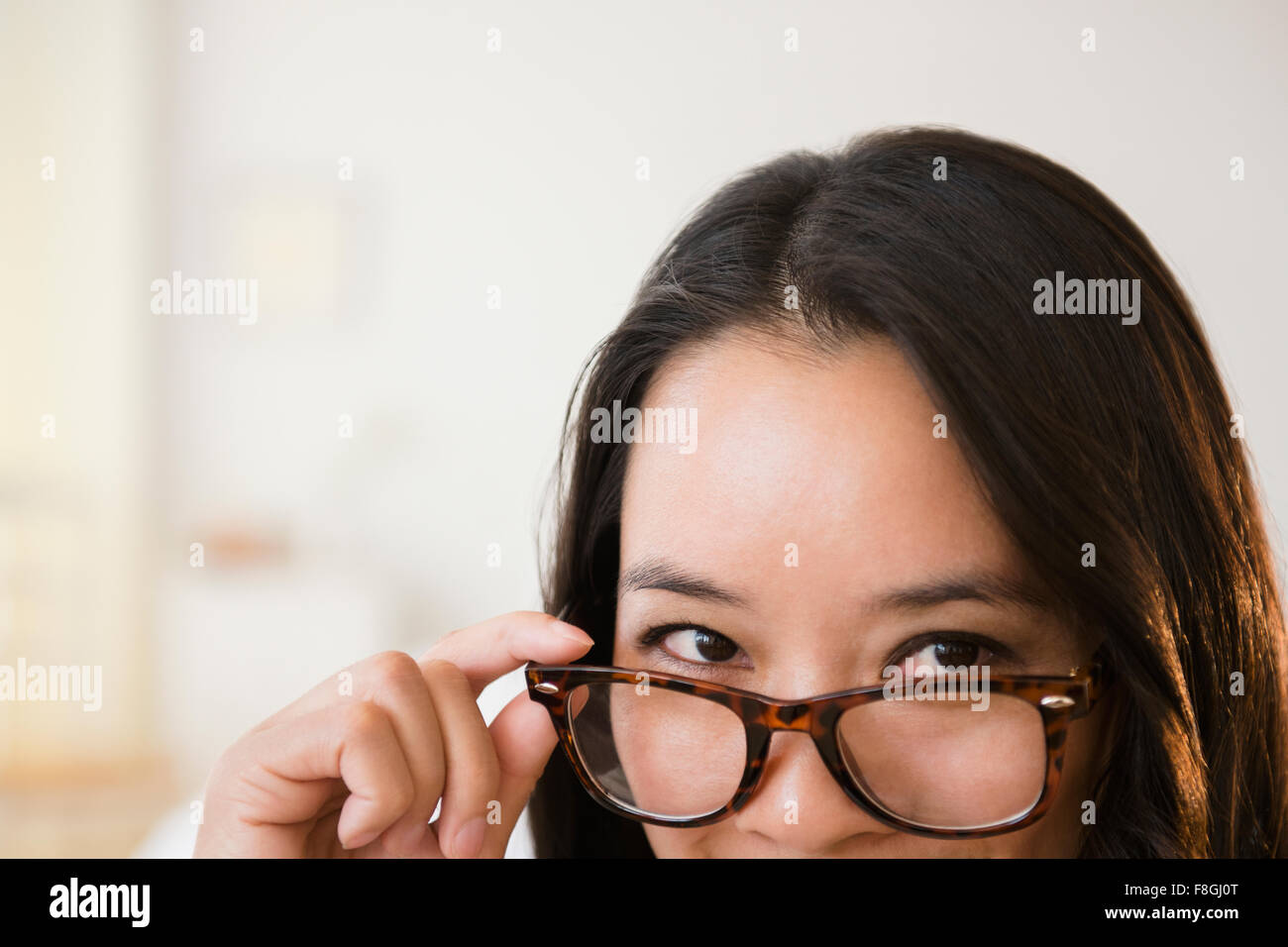 Chinese woman peering over eyeglasses Stock Photo