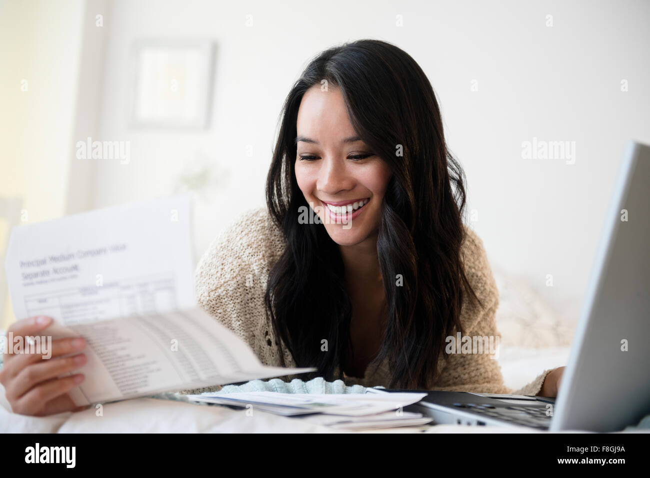 Chinese woman paying bills on laptop Stock Photo