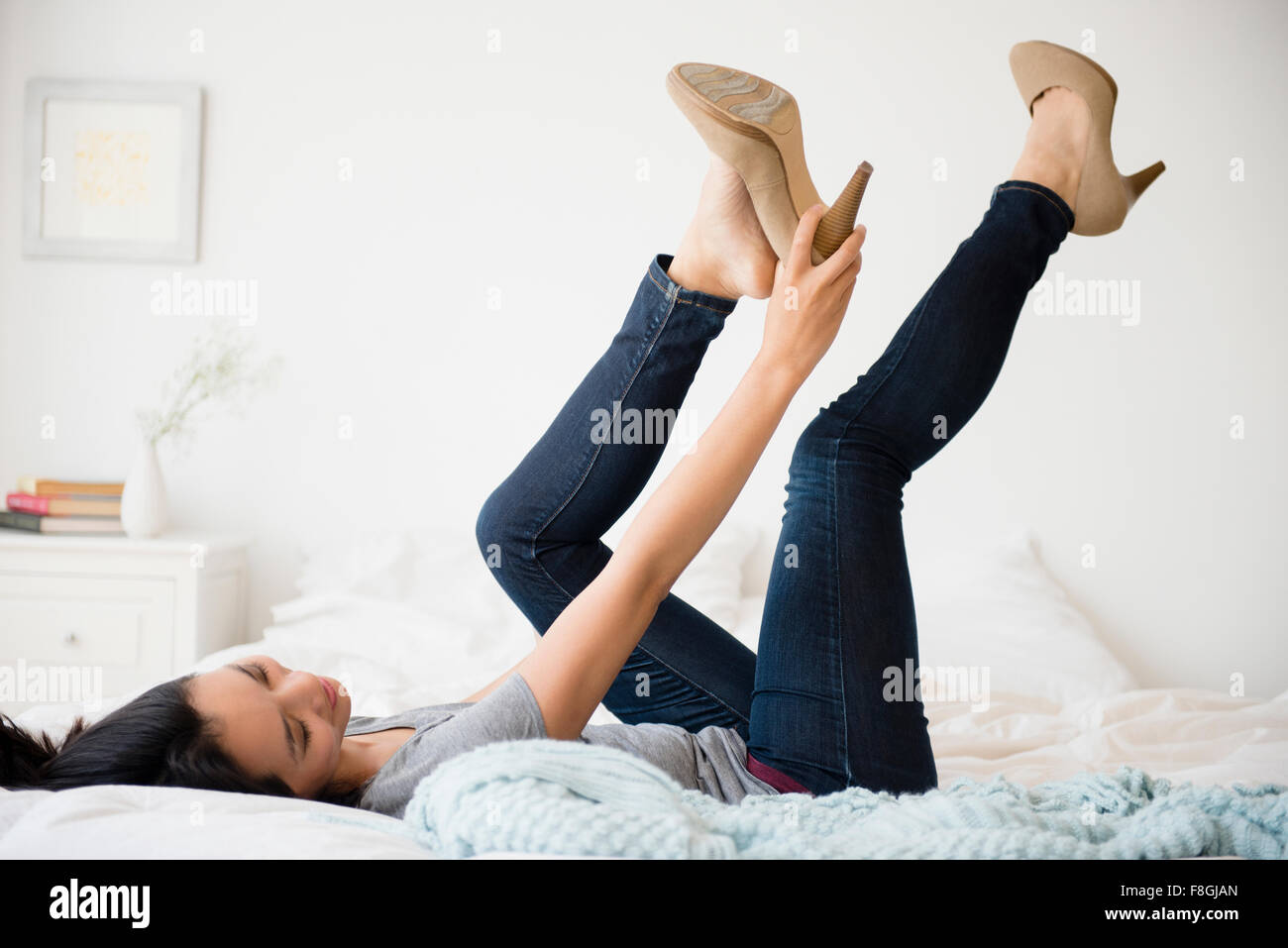 Chinese woman trying on shoes on bed Stock Photo