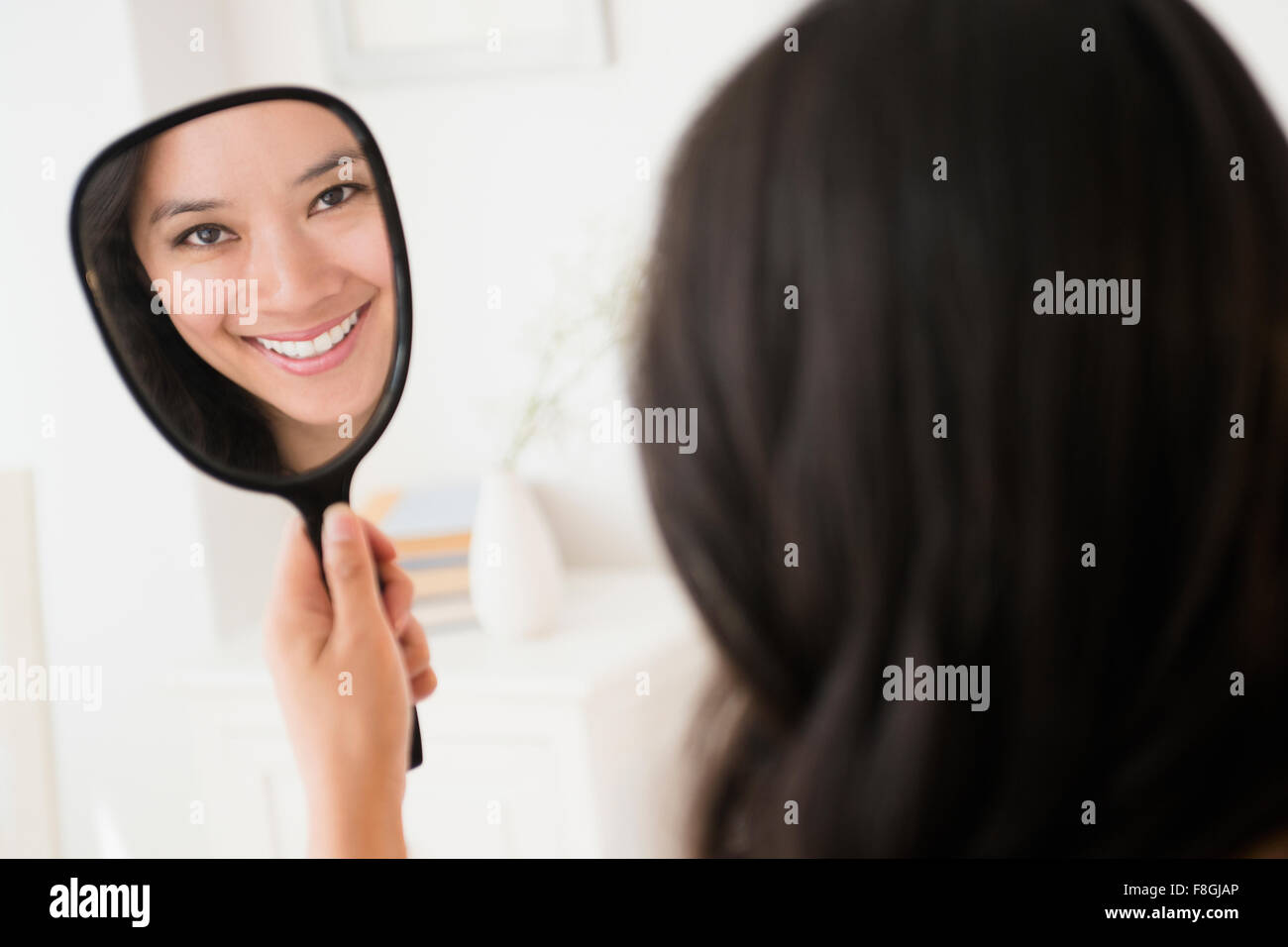 Chinese woman admiring herself in mirror Stock Photo