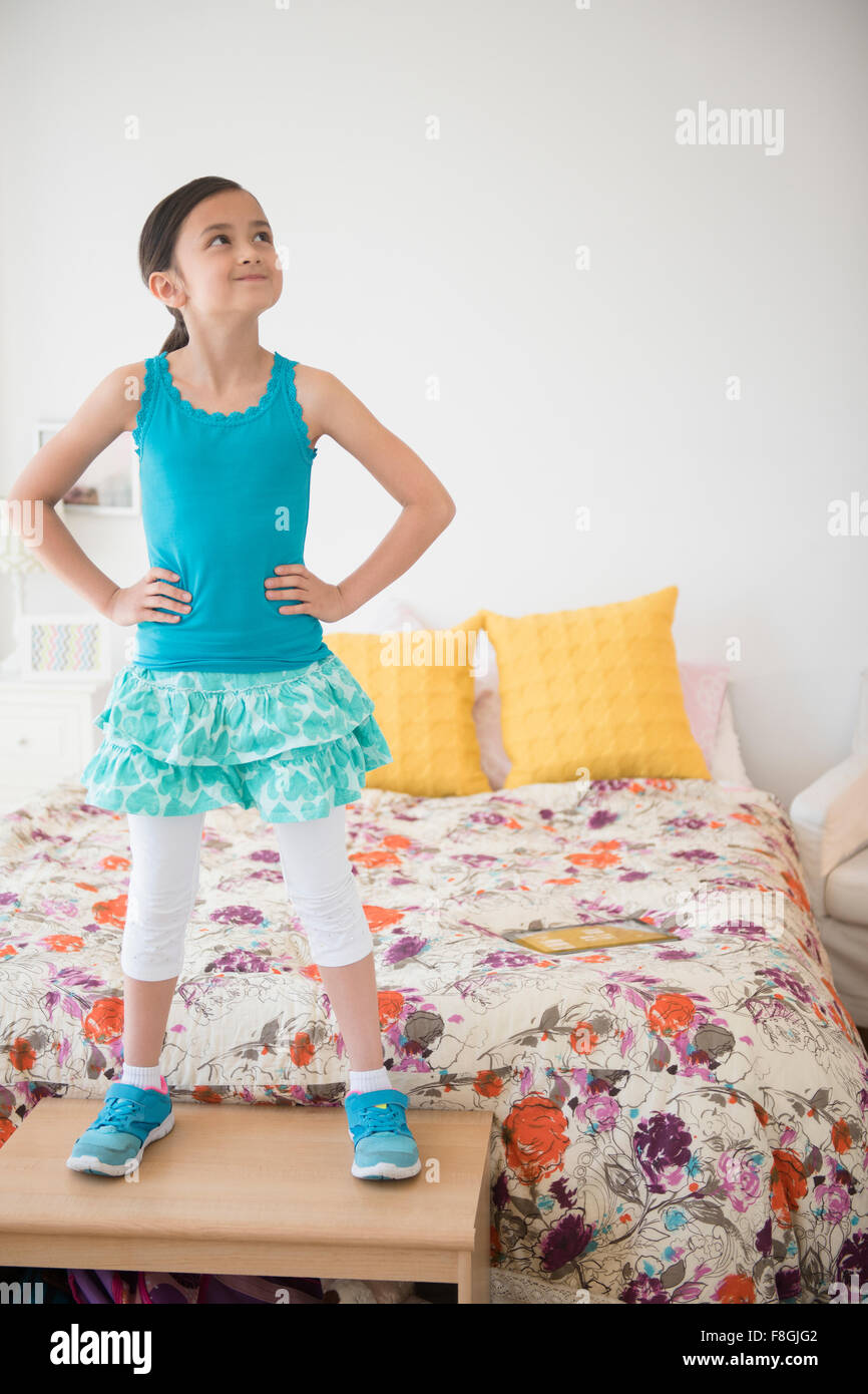 Girl standing on table near bed Stock Photo