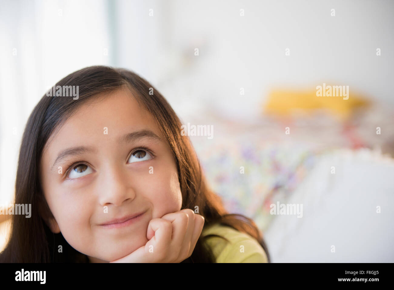 Smiling girl daydreaming with hand on chin Stock Photo