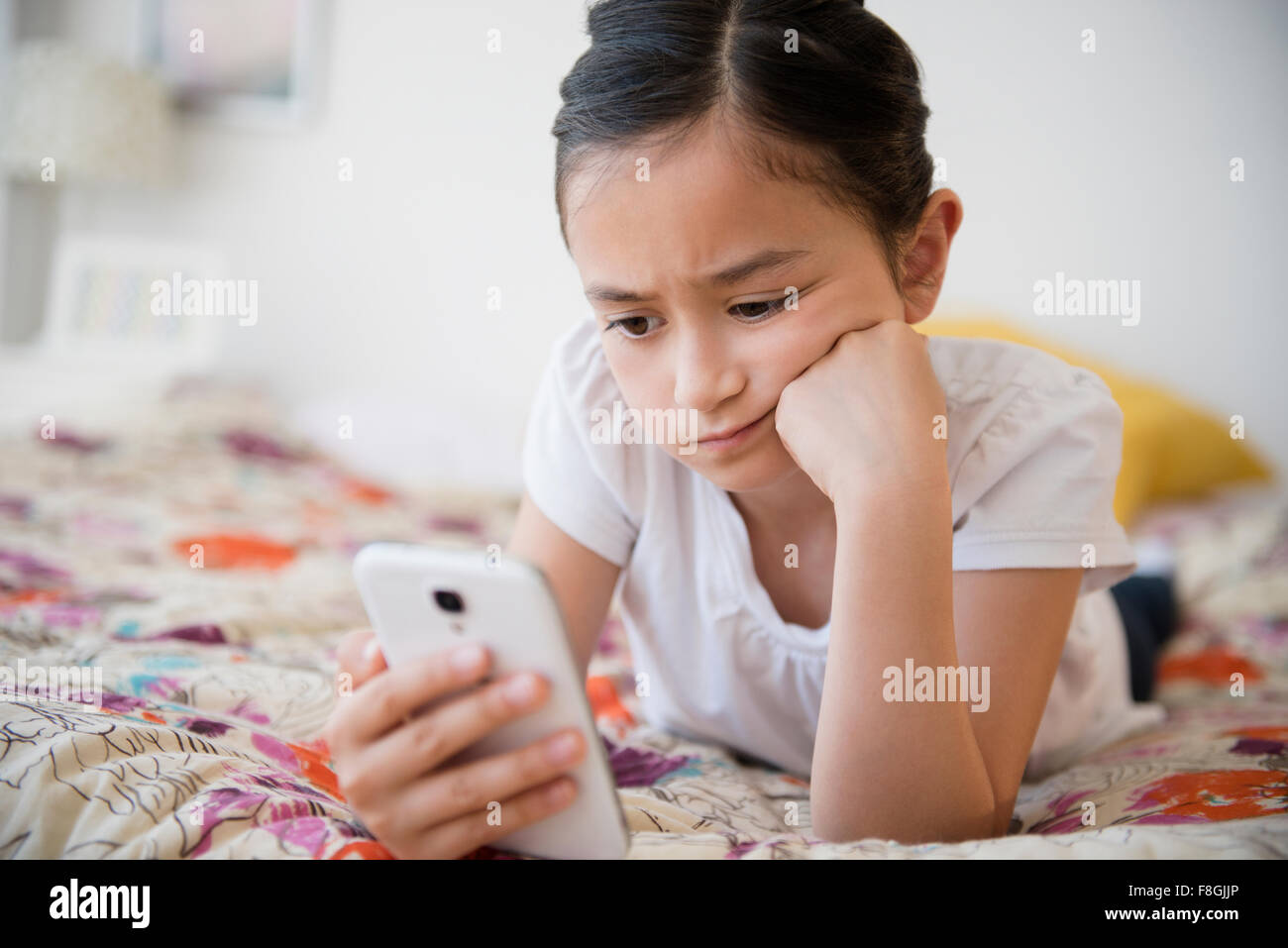 Frustrated girl using cell phone on bed Stock Photo