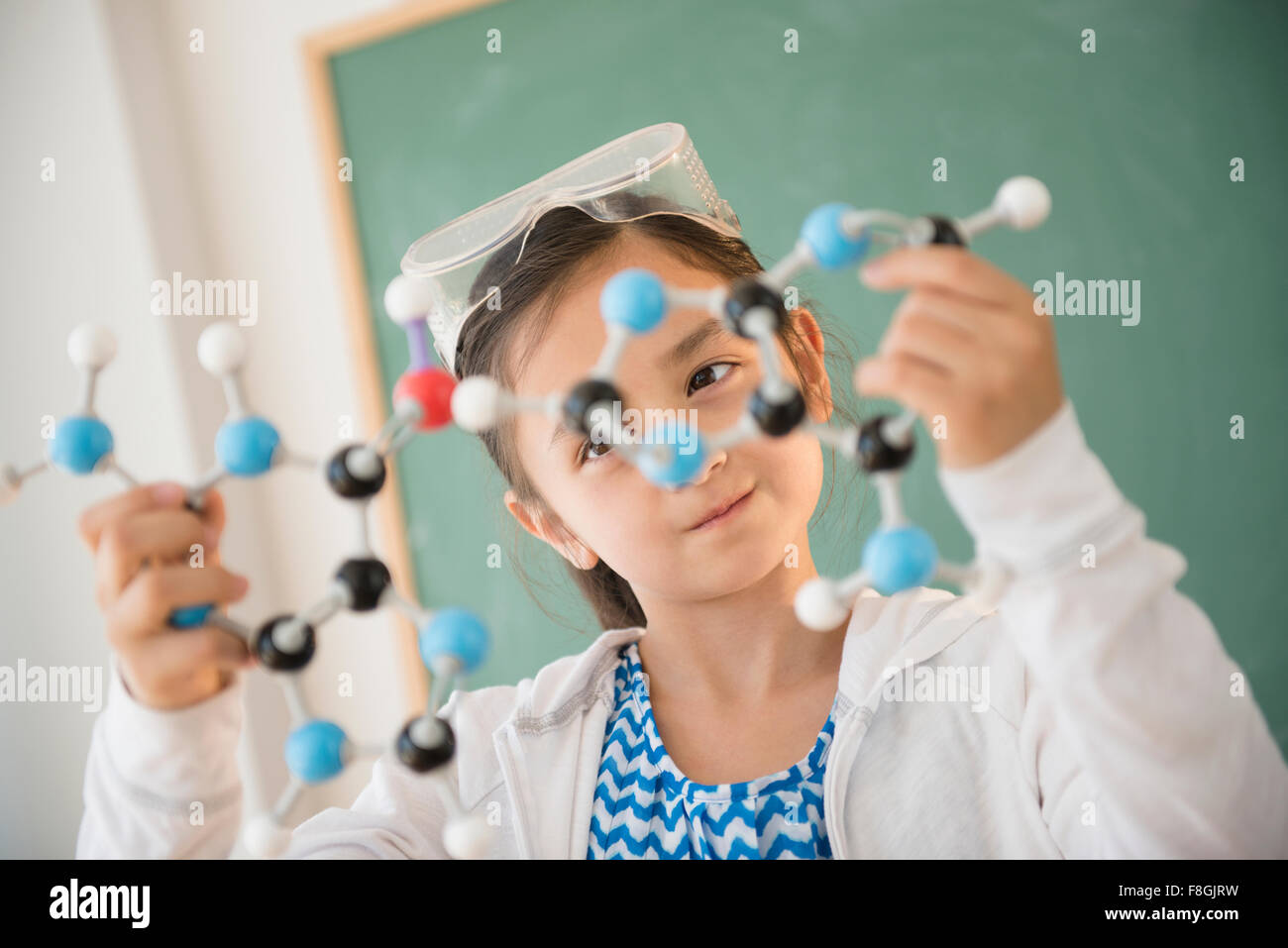 Girl examining molecular model in science class Stock Photo