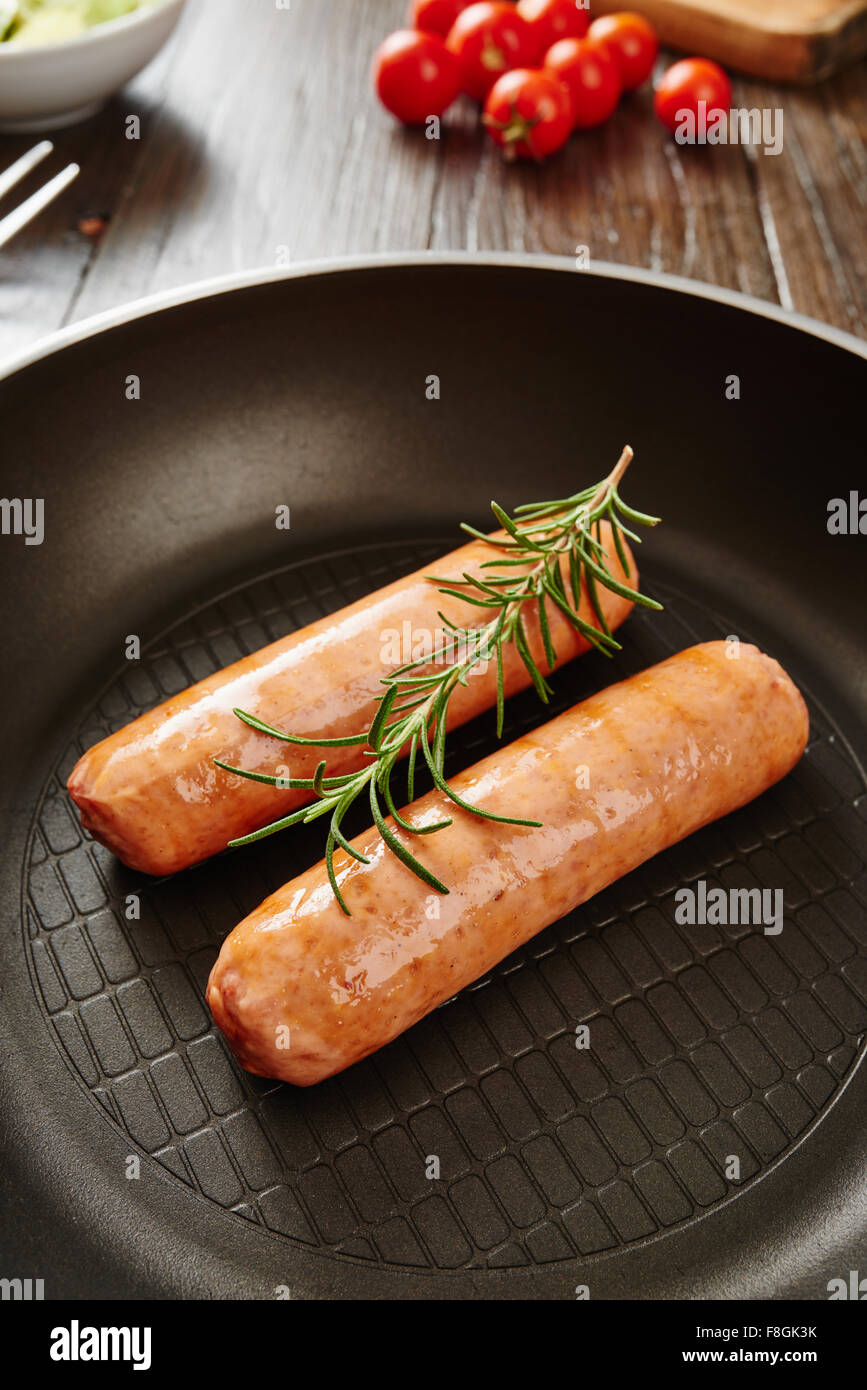 Raw sausage in pan on wooden table surrounded by ingredients Stock Photo