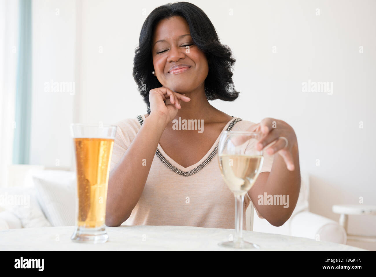 Black woman choosing between white wine and beer Stock Photo