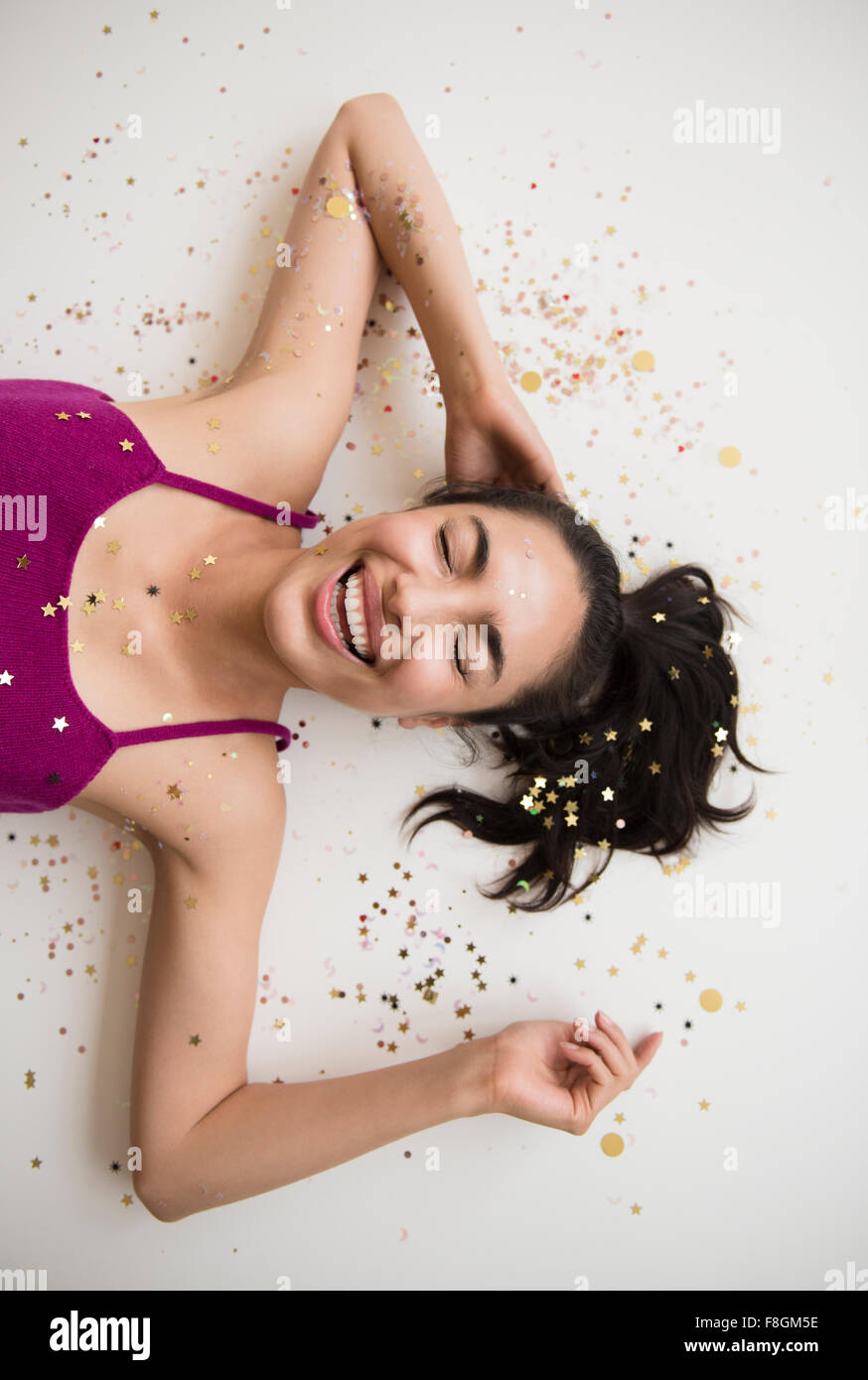 Hispanic woman laying in confetti Stock Photo