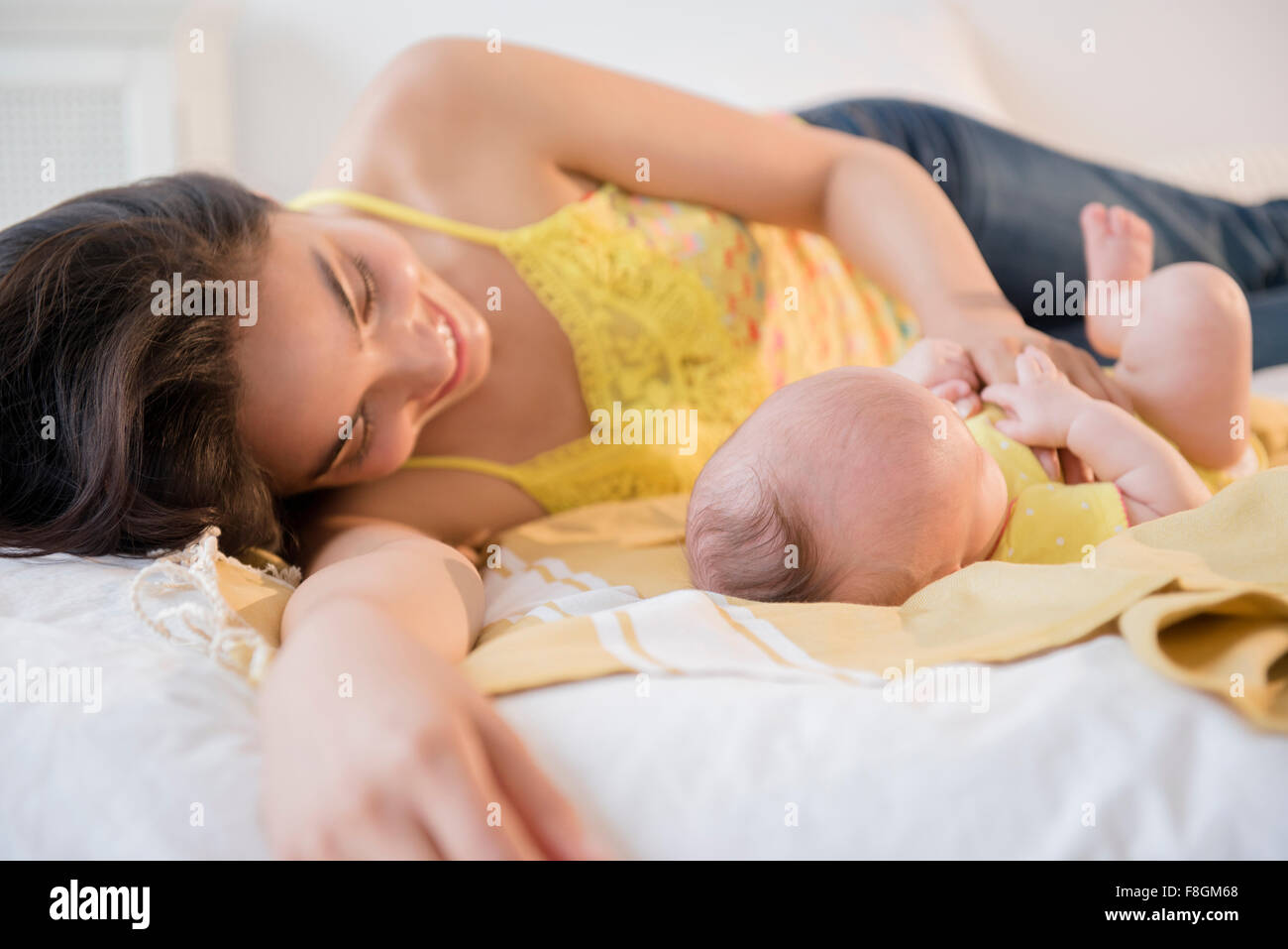 Mother playing with baby daughter on bed Stock Photo