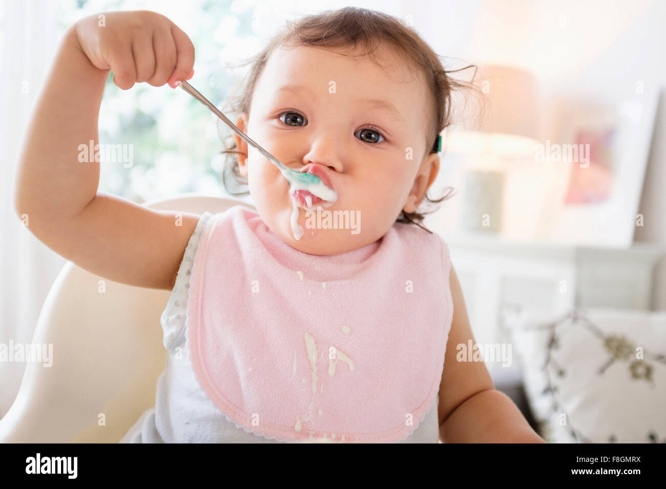 Mixed race baby girl eating yogurt Stock Photo