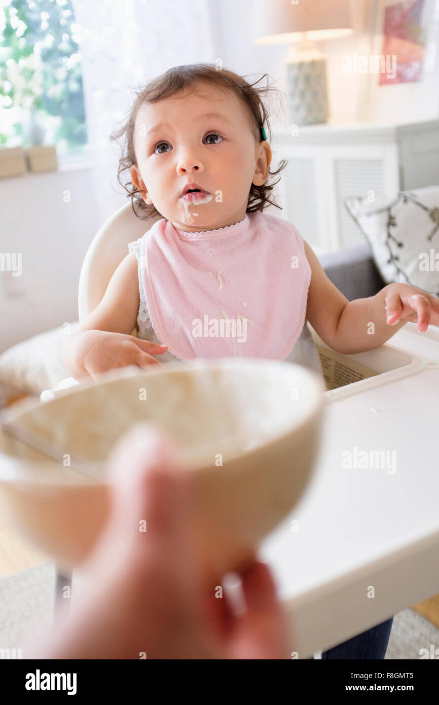 Mother feeding baby daughter in high chair Stock Photo