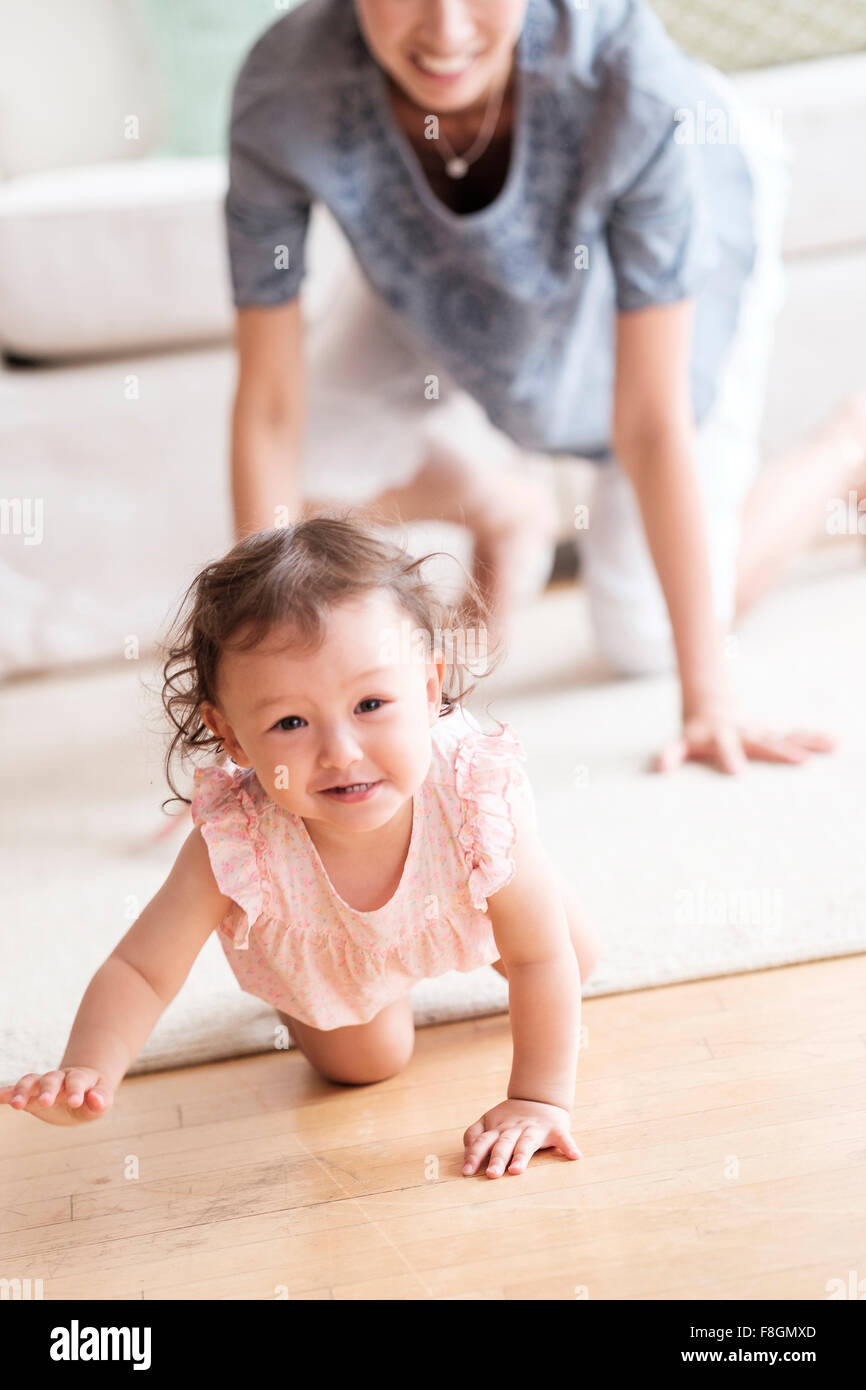 Mother and baby daughter crawling in living room Stock Photo