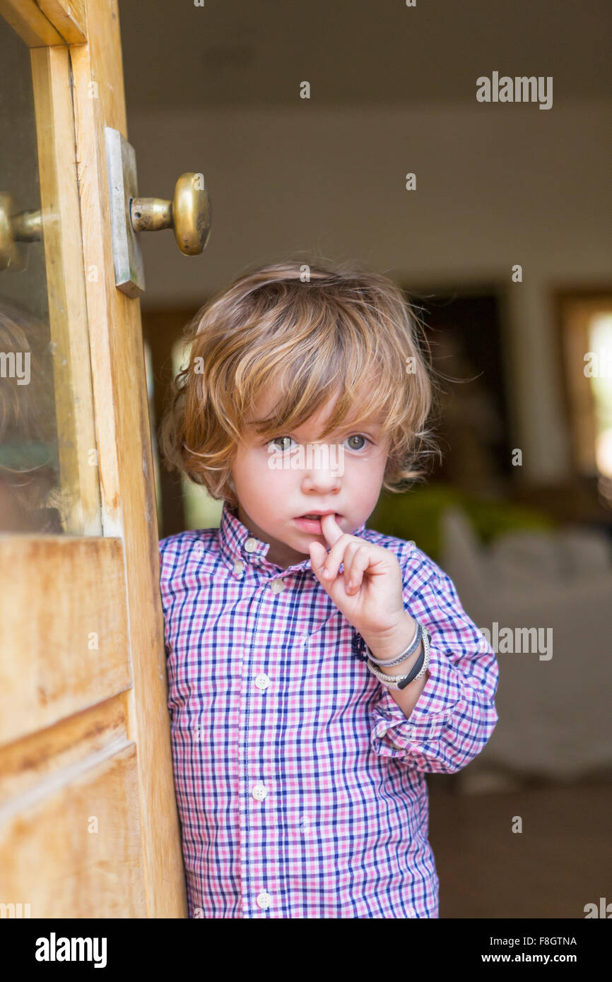 Caucasian boy looking out open door Stock Photo