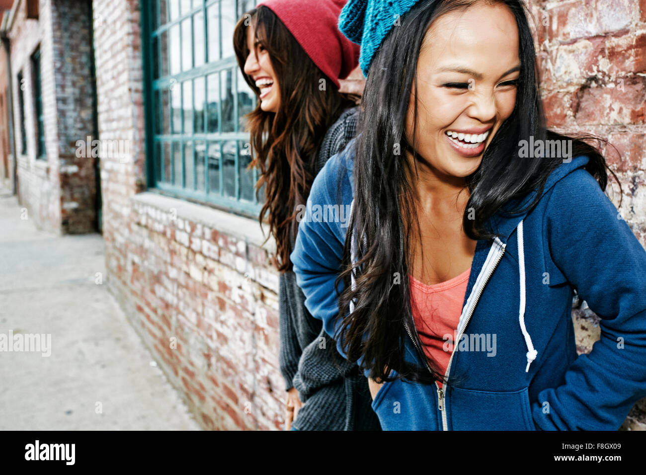 Women laughing in front of brick wall Stock Photo