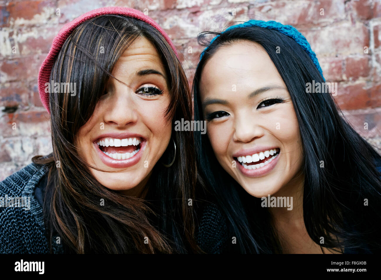 Women laughing in front of brick wall Stock Photo