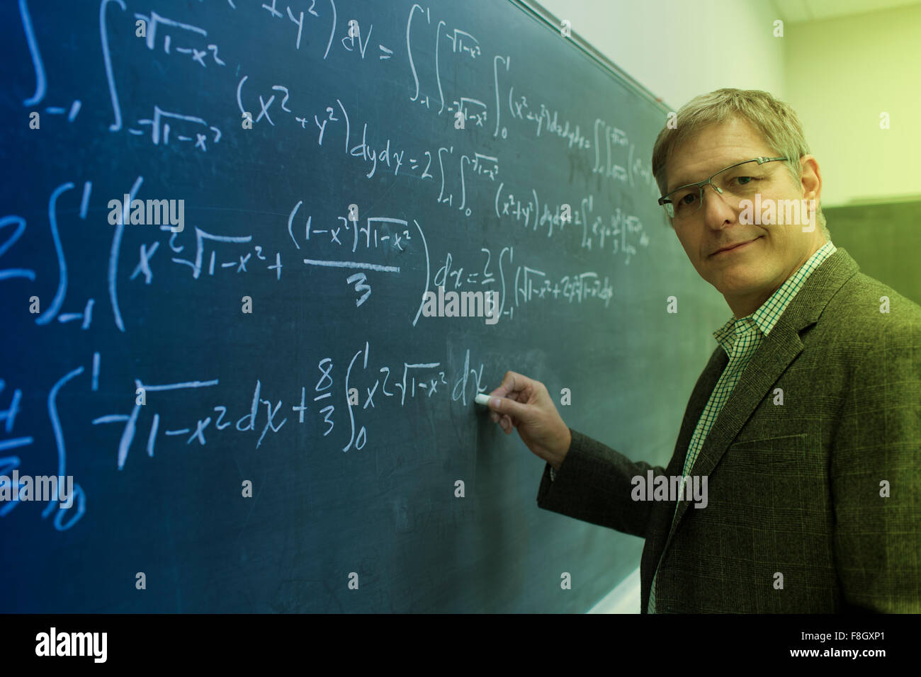 Caucasian teacher writing on chalkboard Stock Photo