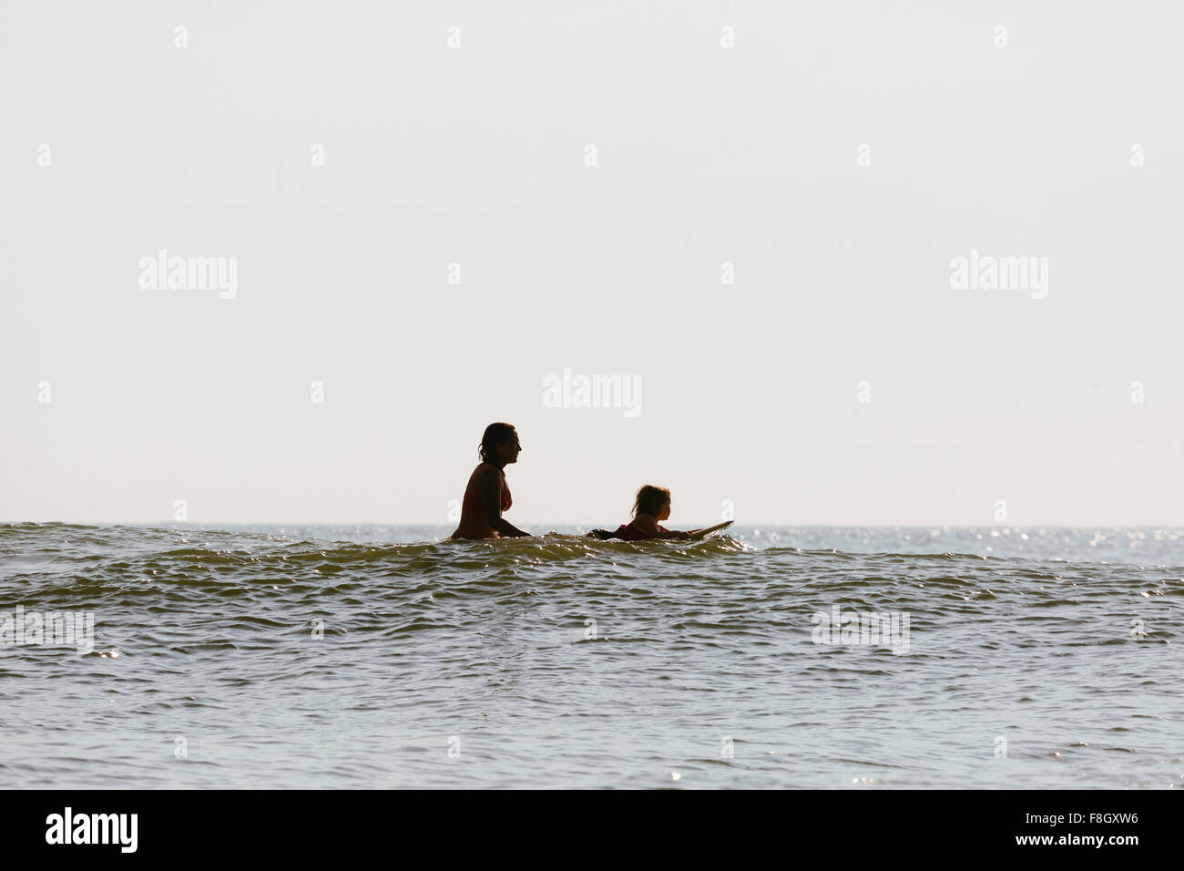 Mother and daughter surfing in waves Stock Photo