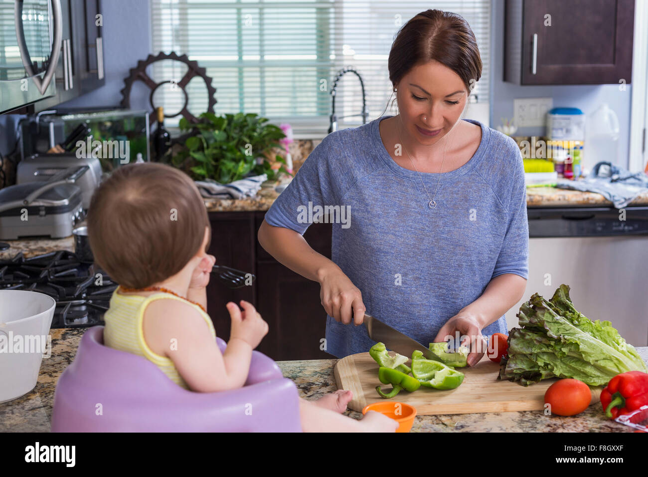 Mixed race mother chopping vegetables with daughter in kitchen Stock Photo