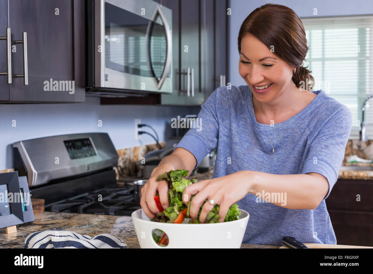 Mixed race woman tossing salad in kitchen Stock Photo