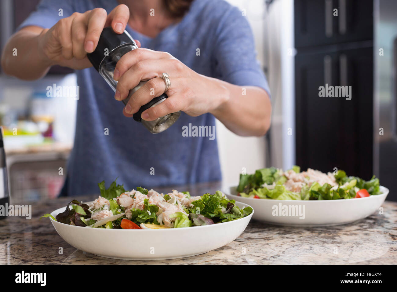 Mixed race woman seasoning salad Stock Photo