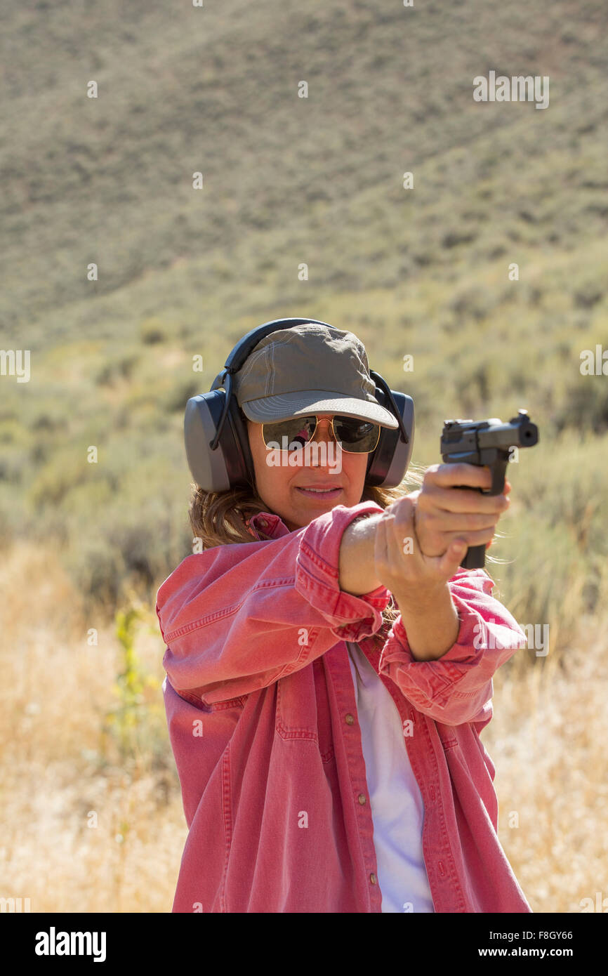 Caucasian woman aiming gun outdoors Stock Photo