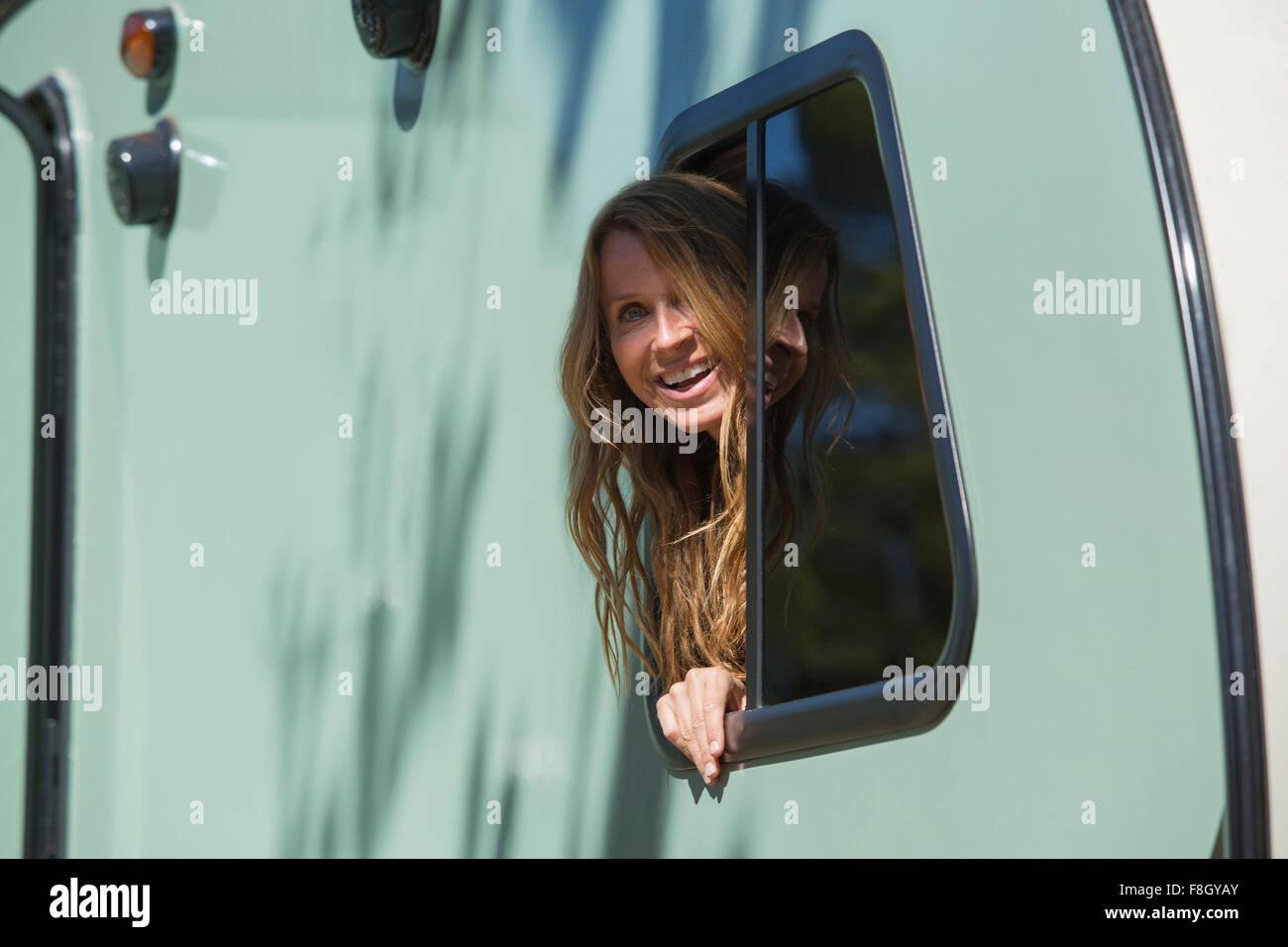 Caucasian woman peering out trailer window Stock Photo