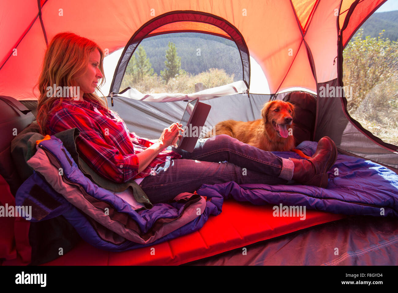 Caucasian woman using digital tablet in camping tent Stock Photo