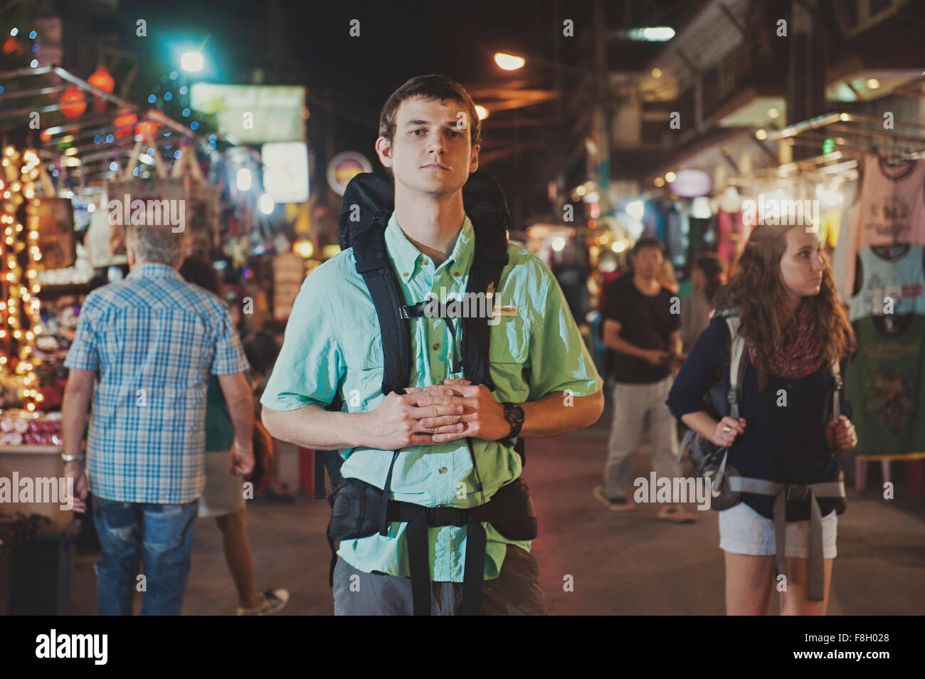 Caucasian tourist standing in market at night Stock Photo