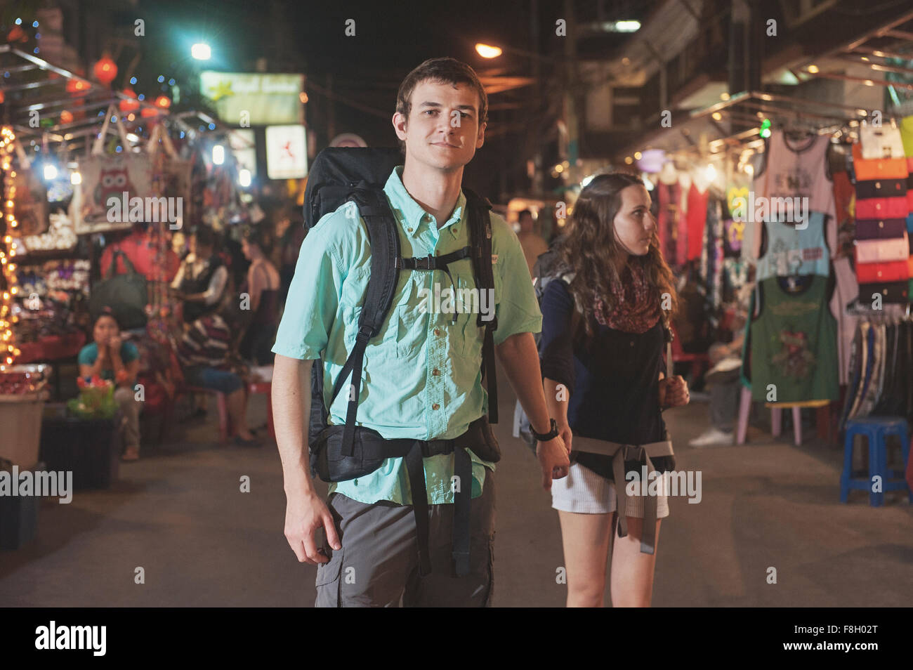 Caucasian tourists holding hands in market at night Stock Photo