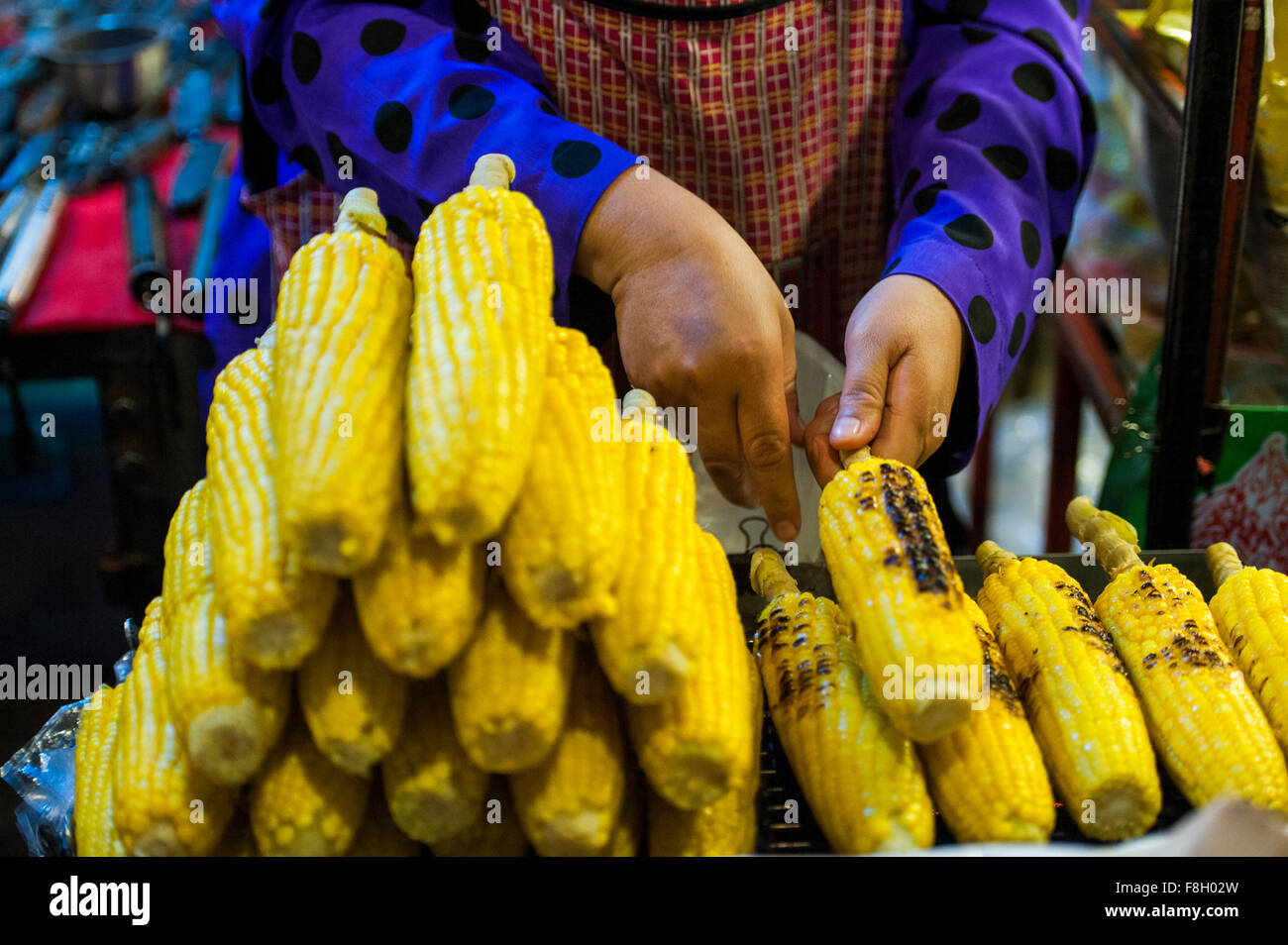 Close up of seller grilling corn at market Stock Photo