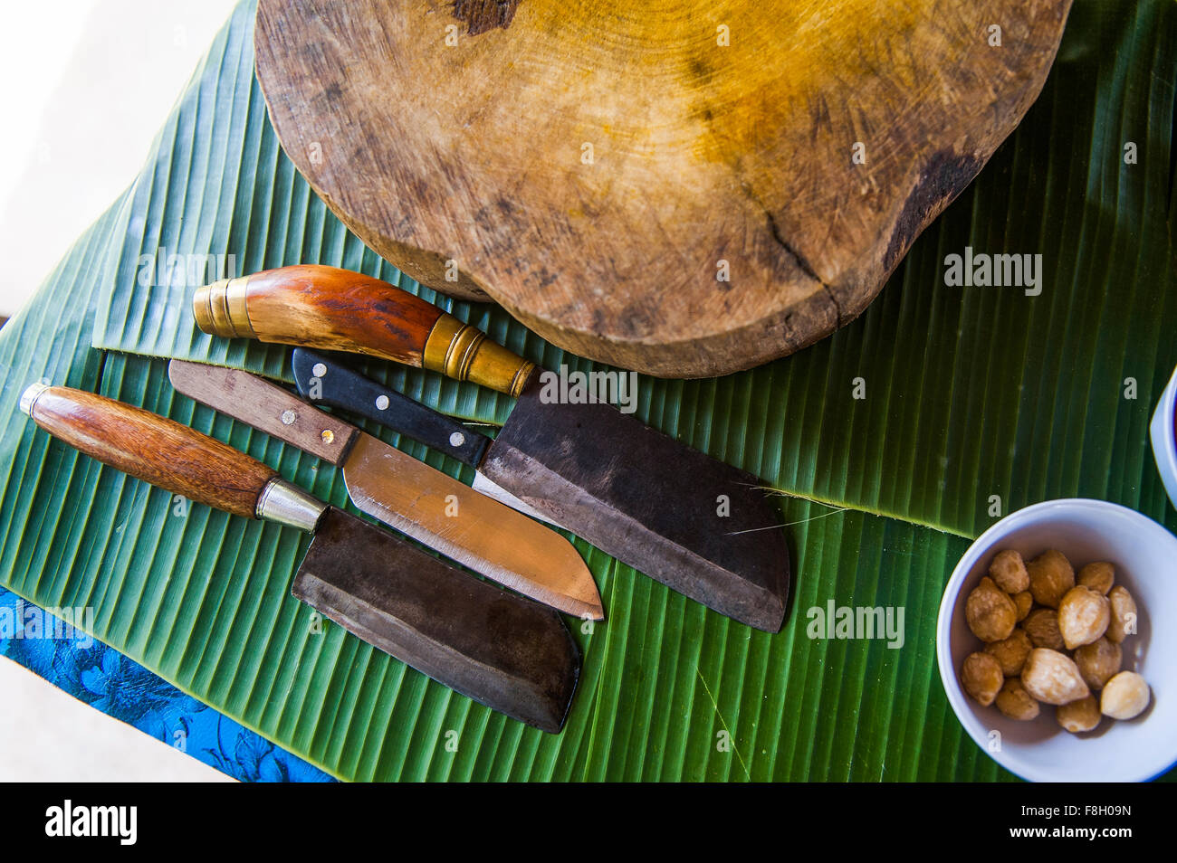 Knives, cutting board and banana leaves on counter Stock Photo