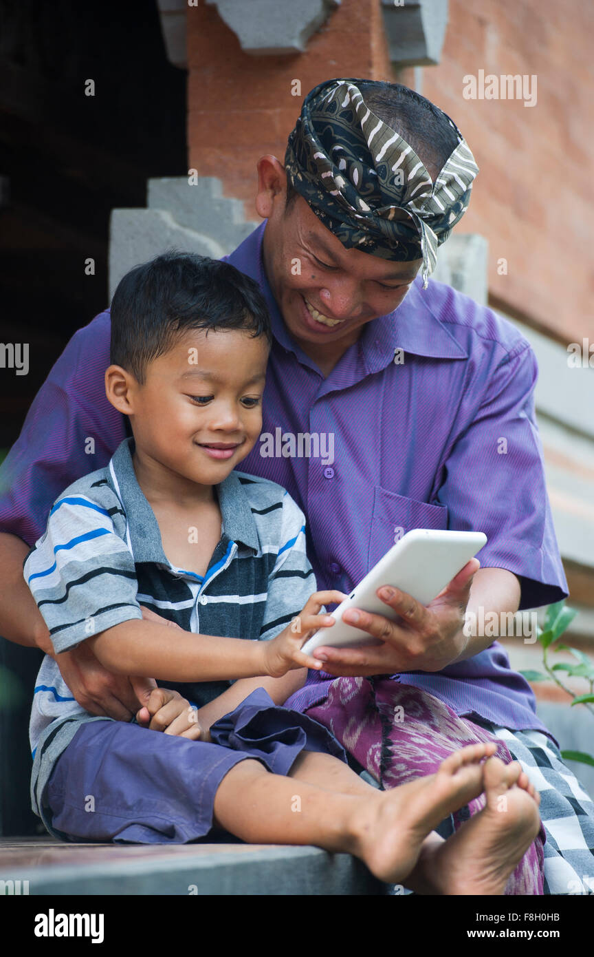 Asian father and son using cell phone outdoors Stock Photo