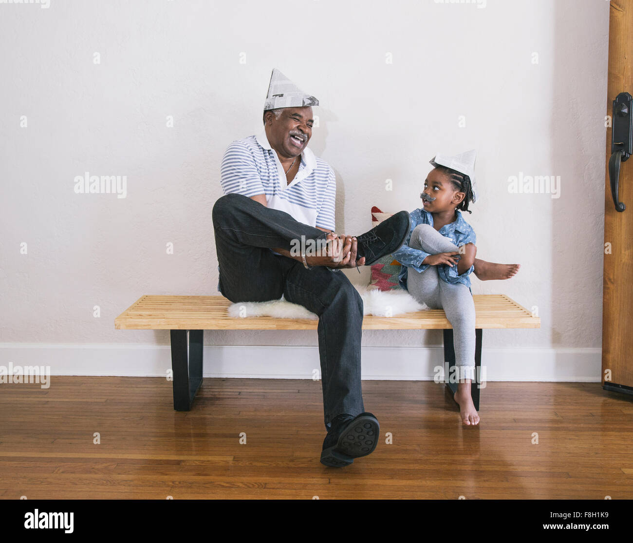 African American grandfather and granddaughter playing on bench Stock Photo