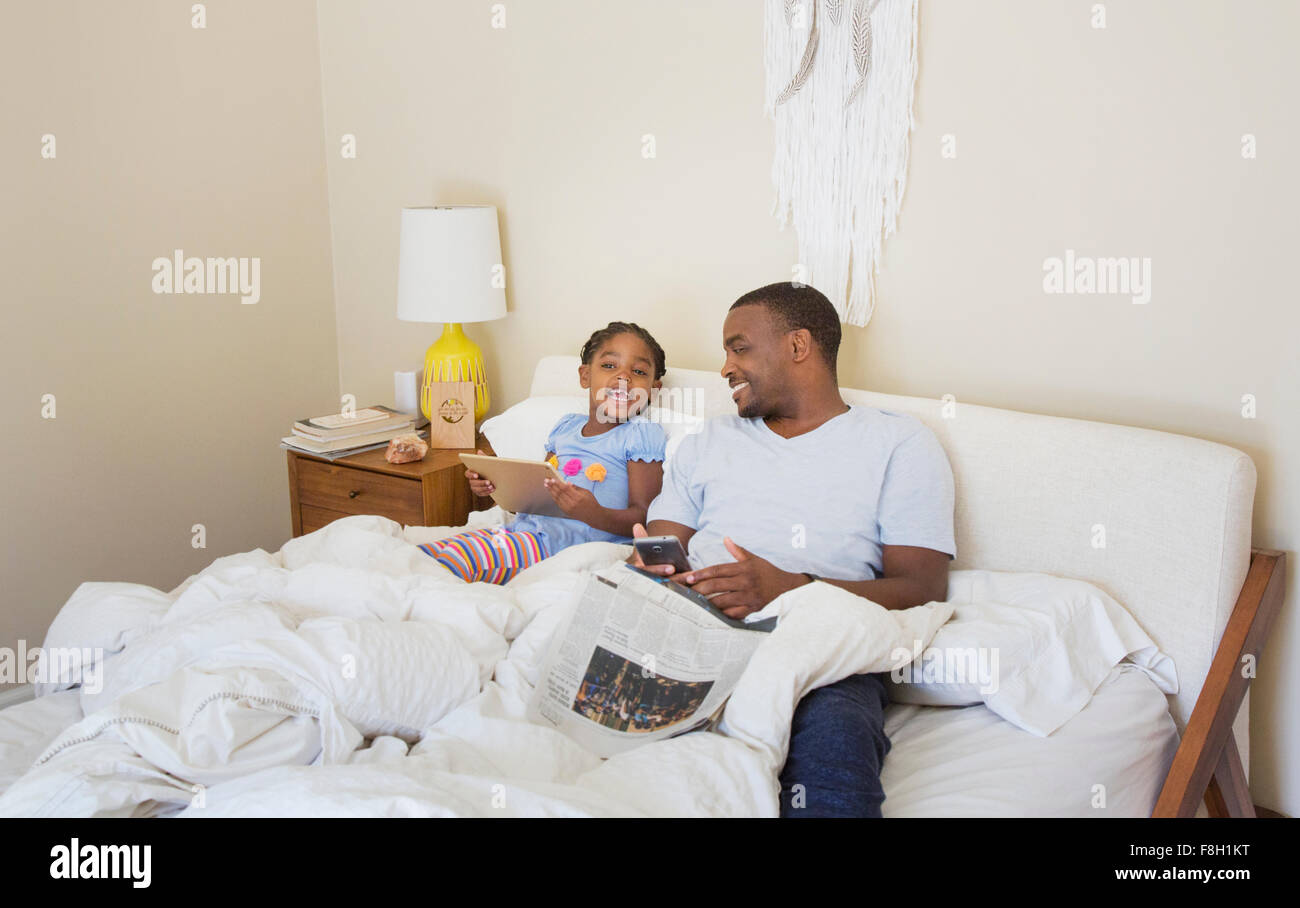 African American father and daughter sitting on bed Stock Photo