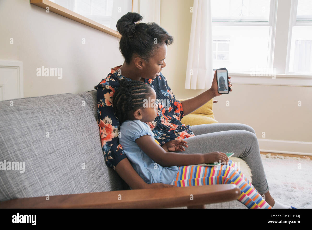 African American mother and daughter video chatting on cell phone Stock Photo