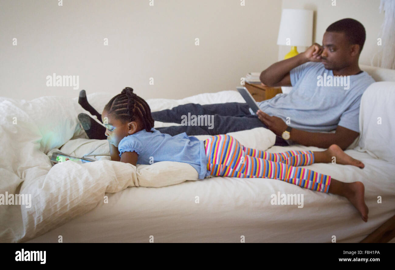 African American father and daughter relaxing on bed Stock Photo